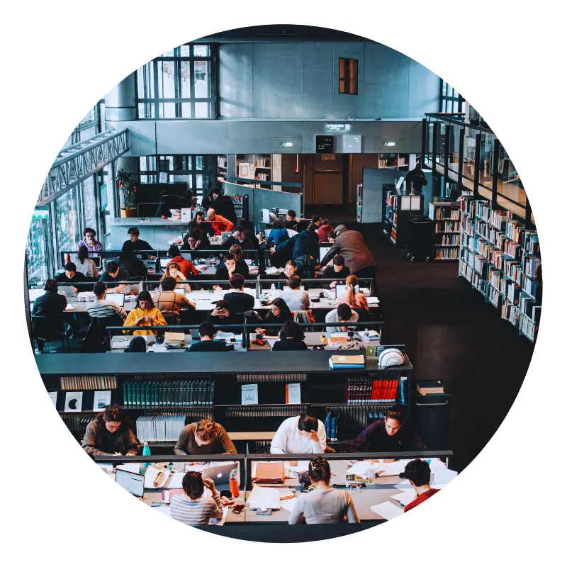 Students studying in a large, busy library.